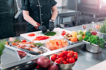 A Woman Chef cuts vegetables in the kitchen in a restaurant.