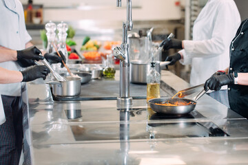 Cooks prepare meals on an electric stove in a professional kitchen in a restaurant or hotel.