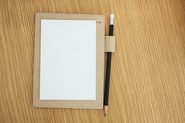 blank notebook with pencil on wooden table background. top view and copy space for your text