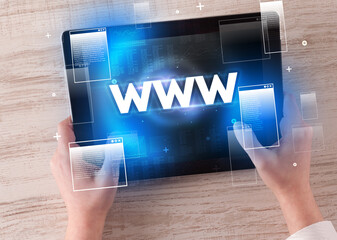 Close-up of a hand holding tablet with WWW abbreviation, modern technology concept