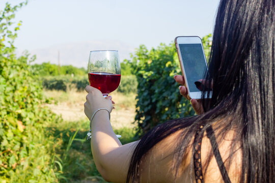 The woman shoots a glass of wine in the grape garden