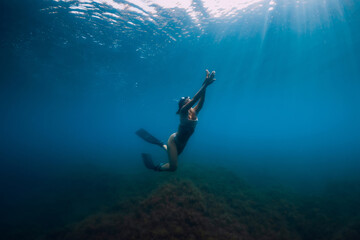 Freediver glides with fins under sea. Woman is doing freediving in the sea