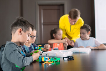Obraz premium Kids creating robots with teacher. Early development, diy, innovation, modern technology concept.