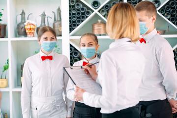 Fototapeta na wymiar Employees of a Restaurant or Hotel in protective masks. End Of Quarantine. Restaurant Manager and his staff on the terrace. interaction with the chef in the restaurant.