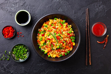 Asian fried rice with egg and vegetables. Dark slate background. Top view.