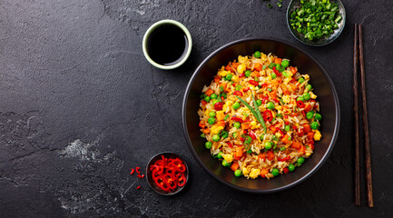 Asian fried rice with egg and vegetables. Dark slate background. Copy space. Top view.