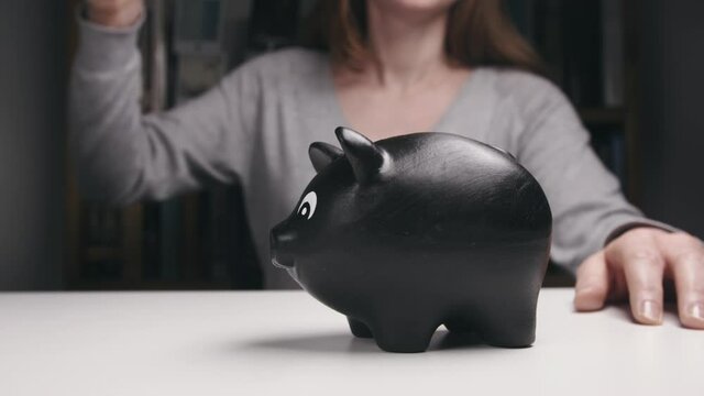 Slow motion shot of a Caucasian woman breaking a piggy bank and collecting the coins.