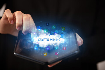 Businessman holding a foldable smartphone with CRYPTO MINING inscription, technology concept