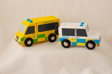 Two painted emergency vehicles wooden toys of an ambulance and a police car isolated on white