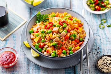 Asian fried rice with ham and vegetables. Blue wooden background. Close up.