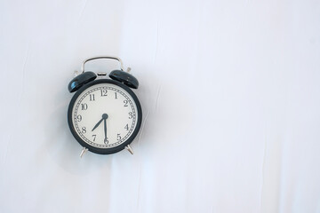 Black retro alarm clock on bed in the morning, wake up, fresh relax, have a nice day and daily routine concept