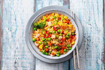 Asian fried rice with ham. Blue wooden background. Close up. Top view.
