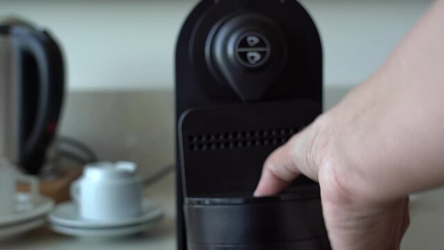 Closeup view of woman taking away used espresso coffee capsule out of coffee machine