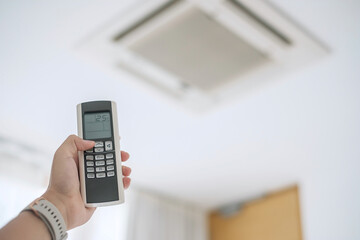 hand using remote controller for adjust Air conditioner inside the room of office or house
