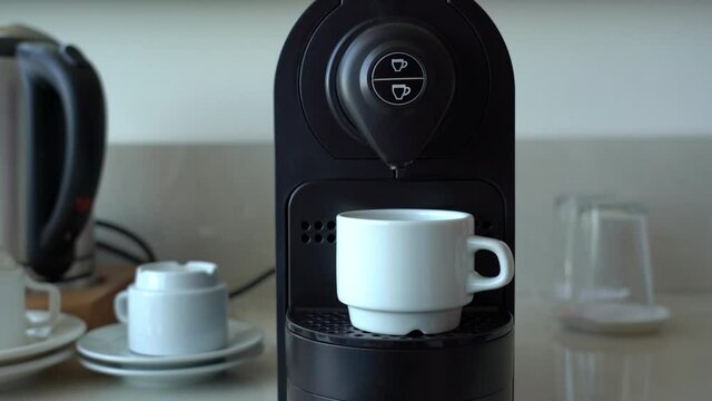 Man makes his morning cup of espresso coffee using small coffee machine