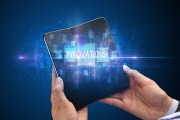 Businessman holding a foldable smartphone with INNOVATIONS inscription, new technology concept
