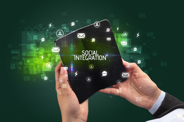 Businessman holding a foldable smartphone with SOCIAL INTEGRATION inscription, social networking concept