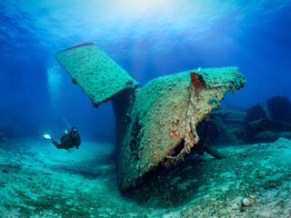 A scuba diver explores a sunken shipwreck in shallow waters of the Aegean Sea, Greece