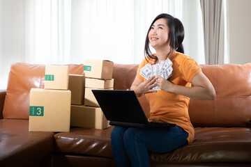 Portrait young woman holding 100 USD dollars banknotes lots are sitting on the sofa at her room at white curtain background