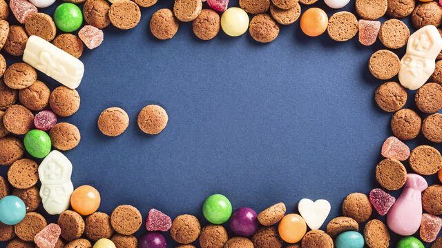 Stop motion animation. Sinterklaas is coming soon, 4K. Dutch holiday St Nicholas day concept with letters, traditional sweets and cookies, kruidnoten on blue background with copy space. Top view.