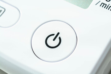 closeup of white power button on device for measuring blood pressure
