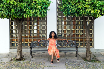 Young ethnic woman sitting on bench in park