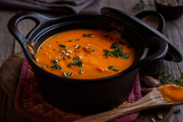 Hot pumpkin soup in cooking pot on dark background