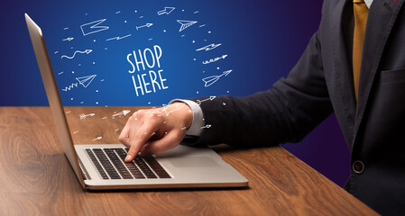 Businessman working on laptop with SHOP HERE inscription, online shopping concept