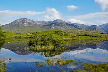 Naklejka na ściany i meble Awe inspiring landscape and lake reflecting Connemara National Park in Ireland