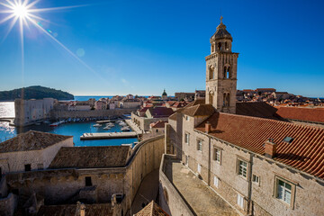 Obraz premium Colorful fortress street walk scene, clear sky sunny day. Church bell tower, building roofs. Winter view of Mediterranean old city Dubrovnik, famous European travel and historic destination, Croatia