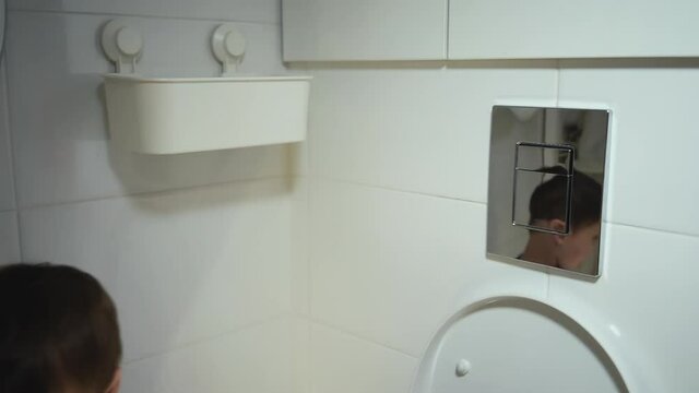 Young boy flush the toilet push the release