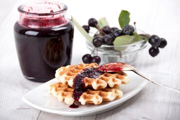 Waffles with chokeberry jam in a white plate