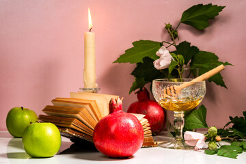 Jar of honey, candle, apples, old book and pomegranates on the table for the holiday of Rosh Hashanah