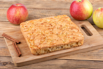 Apple pie sprinkled with cinnamon on a cutting board.