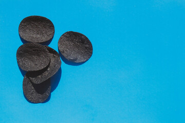 Potato chips in black on a blue background. Creative idea, design. Snacks and beer appetizers. Copy space.
