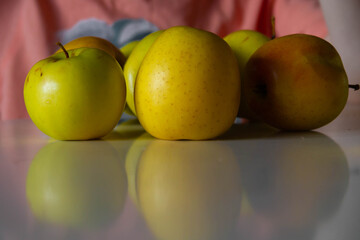 Yellow apples are on the kitchen table.