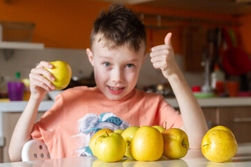 A young European boy likes the taste of an Apple. A child eats a yellow Apple. The boy gives a thumbs up. Benefits of fruit for the body.