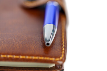 Leather notebook with blue pen isolated on white background. Clo