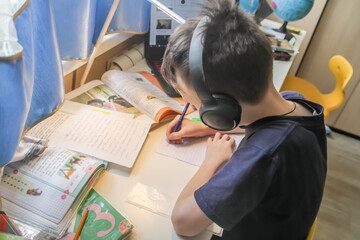 Boy child European schoolboy doing homework at home at the table.