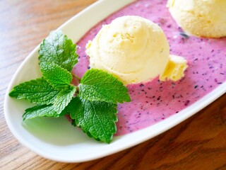 Leckeres Vanilleeis mit Blaubeersauce und Zitronenmelisse