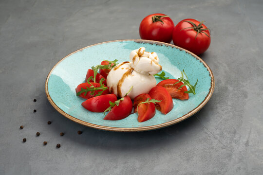 Buratto cheese with tomatoes and arugula on a blue plate