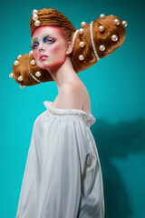 Fashion studio shoot of a caucasian woman with a creative colorful makeup and hairstyle with huge pearls. The concept of hairdressing art.