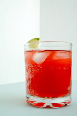 Fototapeta na wymiar Red sparkling drink in the glass with ice and lime