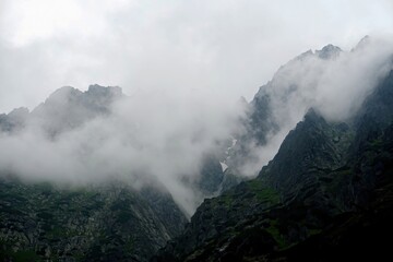 
The peaks of the High Tatras with white clouds. Mountains in the clouds. High Tatras Mountains in Slovakia