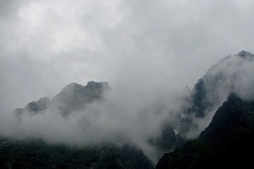 
The peaks of the High Tatras with white clouds. Mountains in the clouds. High Tatras Mountains in Slovakia