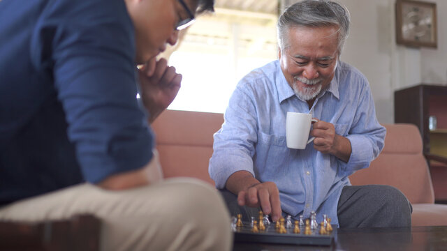 Asian Senior Man Playing Chess With Son