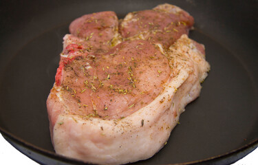 Fresh raw pork steak with spices roasting on frying pan