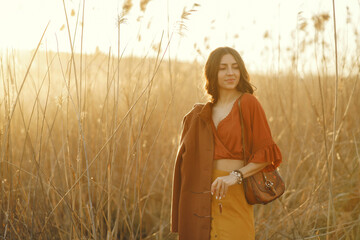 Woman in a summer field. Brunette in a yellow skirt. Girl on a sunset background.