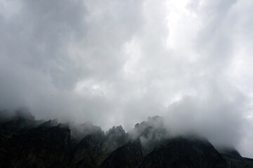 
The peaks of the High Tatras with white clouds. Mountains in the clouds. High Tatras Mountains in Slovakia