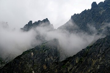 
The peaks of the High Tatras with white clouds. Mountains in the clouds. High Tatras Mountains in Slovakia